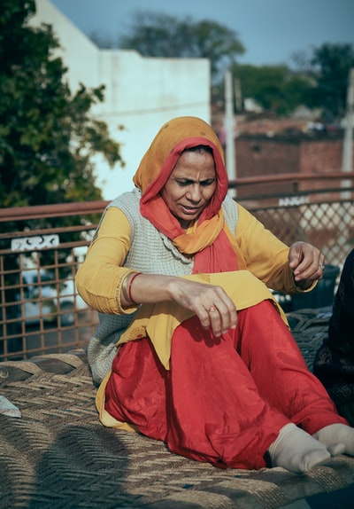 女人在黄色和白色长袖衬衫和红色裤子坐在观众席上混凝土
